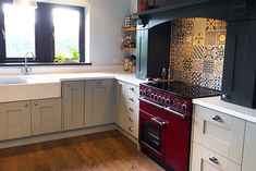 a red stove top oven sitting inside of a kitchen next to a sink and window