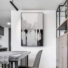 a black and white painting hanging on the wall above a dining room table with two chairs