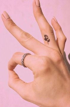 two hands with tattoos on their fingers and one has a flower tattoo on the middle finger