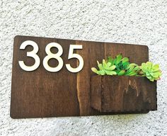 a wooden house number sign with succulents on it