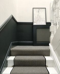 black and white striped carpeted stairs leading up to a framed photograph on the wall