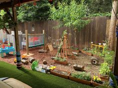 an outdoor play area with lots of plants and toys in the back yard, next to a wooden fence