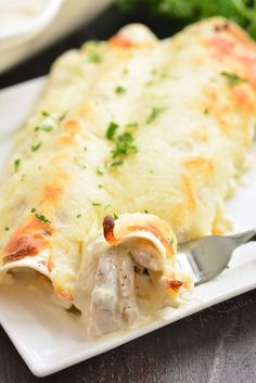 a white plate topped with lasagna covered in cheese and sauce next to a fork