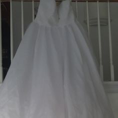 a white dress hanging on a rail in a room