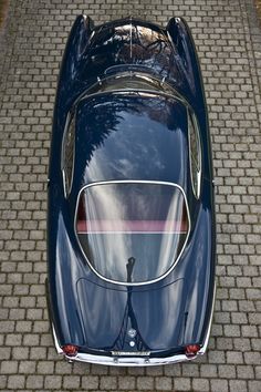 an overhead view of a blue sports car parked on the side of a brick road