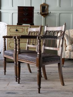 two chairs sitting next to each other in front of a dresser and chair with drawers