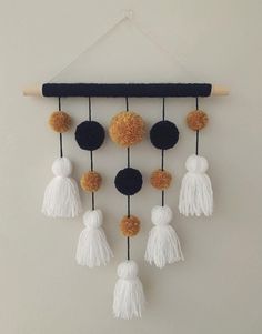 a wall hanging with tassels and pom poms in black, white and gold