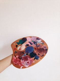 a person holding a paint palette with lots of different colors on it and pointing to the wall