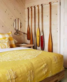 a bed with yellow bedspread and wooden paddles on the wall