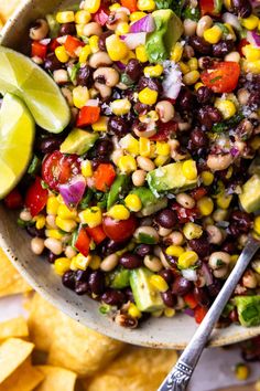 a bowl filled with black eyed peas, corn and avocado next to tortilla chips