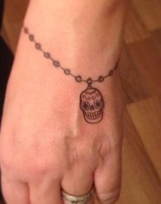 a woman's hand with a tattoo on it that has a skull in the middle