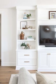 a flat screen tv mounted on top of a white bookcase in a living room