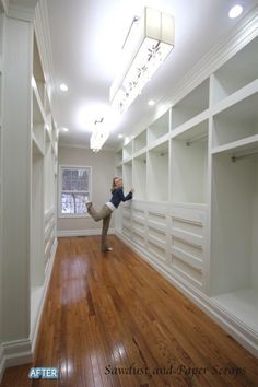 a woman standing in the middle of a room with white shelving and wood floors