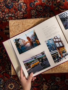 an open book with pictures on it sitting on top of a table next to a person's hand