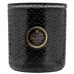 a black candle that is sitting on top of a white surface with the words voluspa written in gold