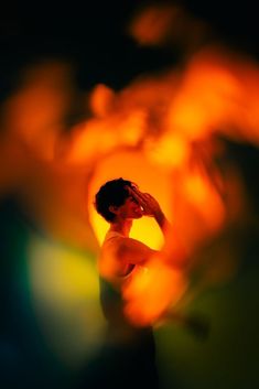 a blurry image of a person holding their head in front of an orange flower