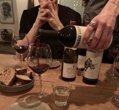 a person pouring wine into a glass at a table