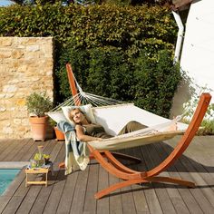 a woman laying in a hammock next to a pool with a potted plant