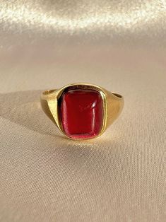 Antique 18k yellow gold ring from the United Kingdom. This signet ring features a vibrant synthetic ruby cabochon.  Great antique condition Size: 7.5 resizable** Weight: 3.5 grams Band: 11.1 mm (front), 1.7 mm (back) Synth Ruby: 8.3 mm x 10.0 mm  Hallmarks:18CT Please note, vintage and antique jewelry may come with imperfections commensurate of their age. To see more photos and videos of this piece, visit our Instagram: www.instagram.com/23carat PLEASE READ ALL POLICIES regarding shipping, returns, tax, etc Yellow Gold Cabochon Ruby Ring, Gold Ruby Ring Oval Cabochon With Polished Finish, Formal Gold Cabochon Signet Ring, Gold Domed Ruby Ring With Gemstone, Gold Ruby Ring With Domed Shape, Classic Yellow Gold Signet Ring With Cabochon, Modern Gold Signet Ring With Cabochon, Formal Ruby Signet Ring, Yellow Gold Ruby Signet Ring With Polished Finish