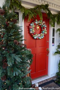 a red door decorated with christmas wreaths and pine cones