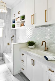 a kitchen with white cabinets and marble counter tops, gold faucets and brass pulls