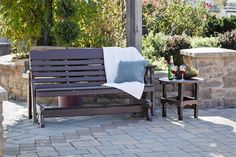 a wooden bench sitting on top of a brick patio next to a table and chairs