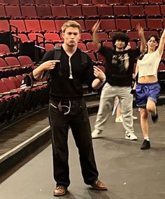 three people standing in front of an empty auditorium with their arms up and hands raised