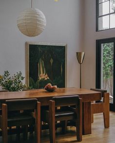 a dining room table with chairs and a painting on the wall in front of it