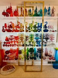 there are many different colored glass vases on the shelves in this room, including one that has a ladder