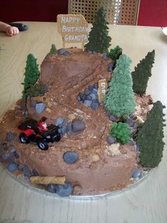 a birthday cake made to look like a dirt road with trees and rocks on it