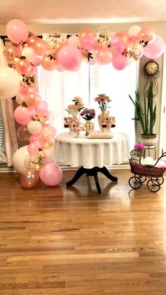 a table topped with lots of pink and white cake next to balloons in the air