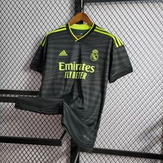 a soccer jersey hanging on a fence next to a hanger with the name emirates