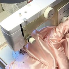 the sewing machine is next to pink fabric