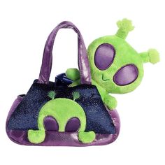 a purple and green purse with an alien face on it's side, sitting next to a stuffed animal