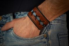 a man's hand wearing a leather bracelet with an arrow design on the wrist