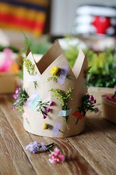 a paper crown sitting on top of a wooden table next to flowers and other plants