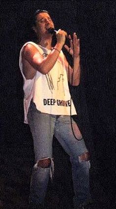 a woman singing into a microphone while wearing ripped jeans and a t - shirt with the words deep purple printed on it