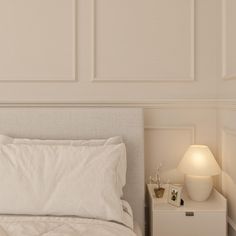 a white bed sitting next to a night stand with a lamp on top of it