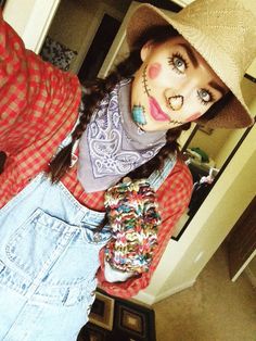 a woman with makeup on her face is wearing overalls and a straw fedora