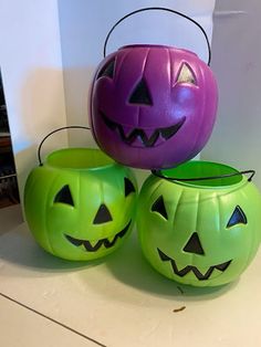 three plastic pumpkins with faces on them sitting in front of a white wall and a mirror