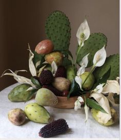 a bowl filled with fruit and flowers on top of a table