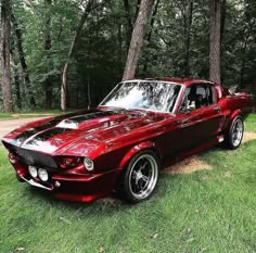 a red car parked in the grass near some trees