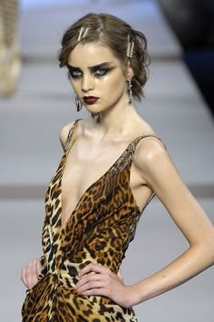 a woman in a leopard print dress with black eyeliners on the catwalk