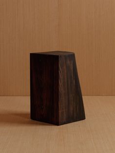 a small wooden object sitting on top of a wood table next to a brown wall