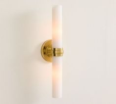 a wall light that is on the side of a white wall with a gold finish