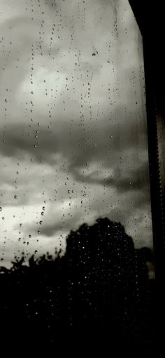 rain drops are falling on the window pane as it looks out into the distance