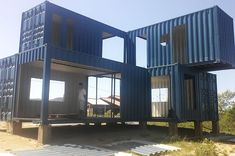 two large blue shipping containers sitting on top of a dirt field