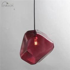 a red light hanging from a ceiling with a white wall in the background and an unox logo on it