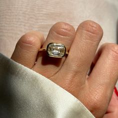 a close up of a person's hand holding a ring with a diamond in it