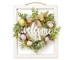 a welcome sign hanging on the wall with an easter wreath in front of it that says,'welcome '